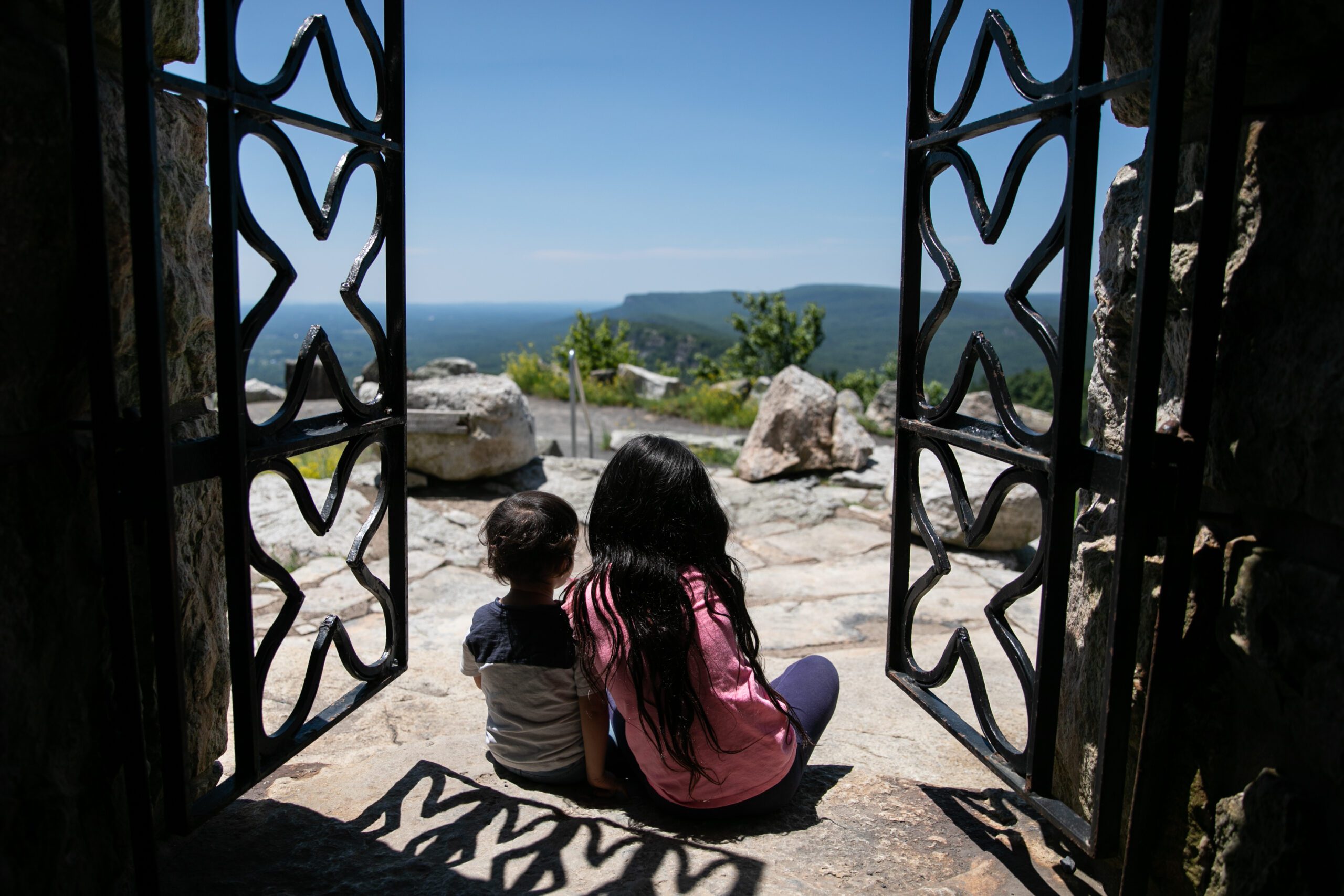 2 kids sitting with gate doors open facing a beautiful view